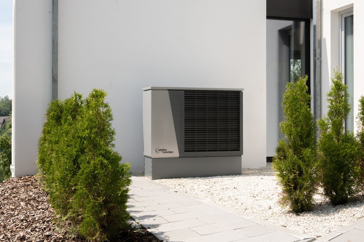 Neu installierte Luft-Wärmepumpe vor einem Wohnhaus